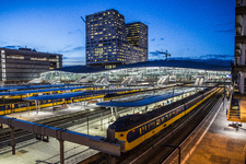 909010 Gezicht op het Centraal Station te Utrecht, vanaf de Moreelsebrug, bij avond, met op de achtergrond de ...